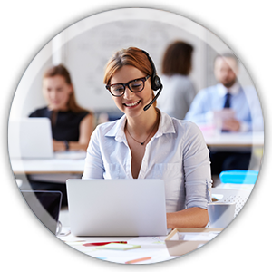 Frau mit Brille und Headset sitzt lächelnd am Laptop